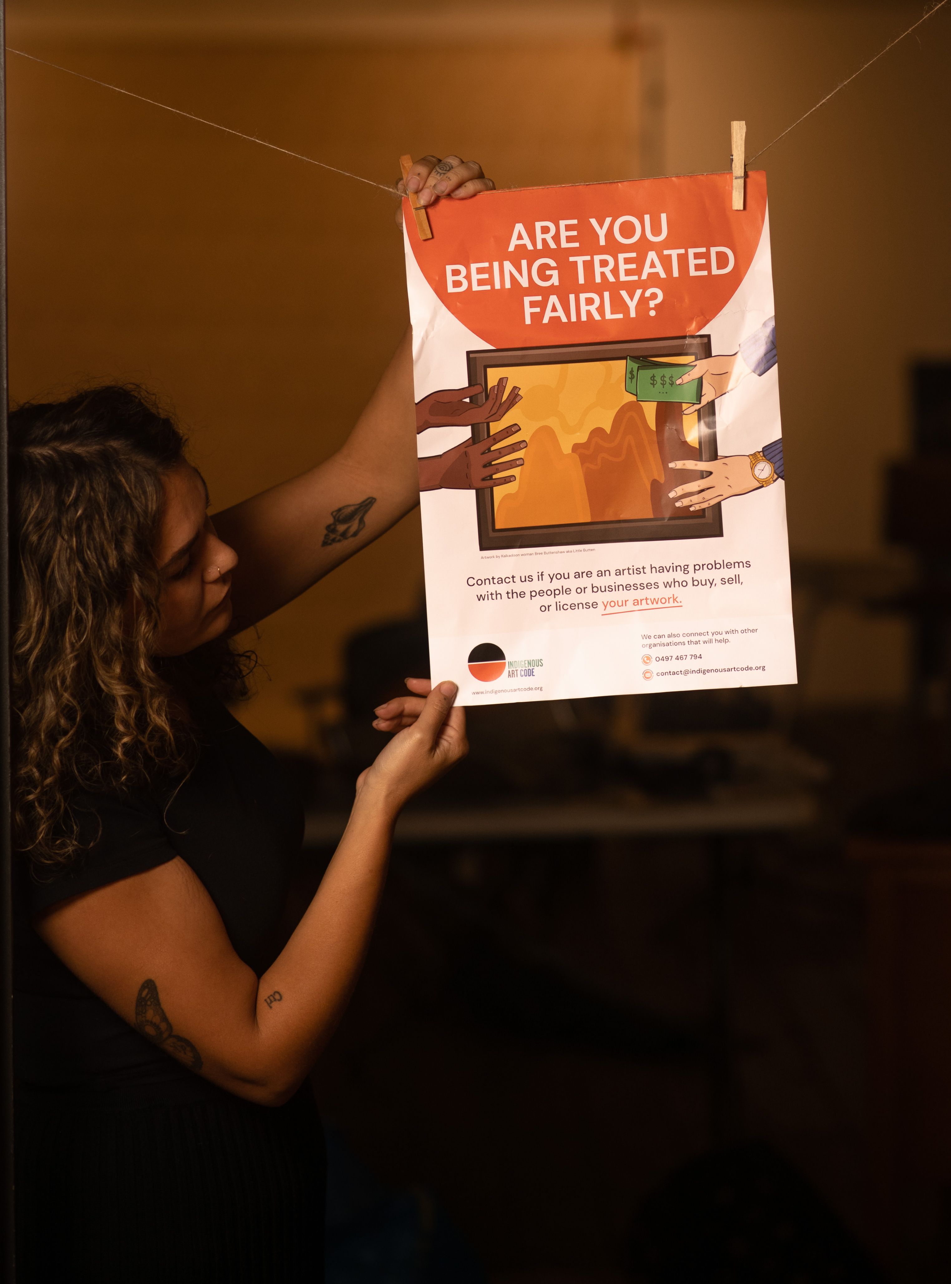 Savannah Travia-Dann with the Indigenous Art Code 'Are you Getting a Fair Go?' poster. Photo by Cole Baxter